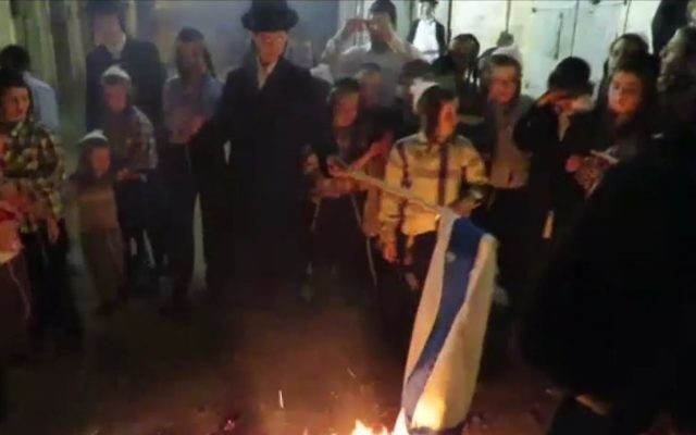 Des juifs ultra-orthodoxes brûlent un drapeau israélien à Mea Shéarim durant le 69ème anniversaire de l'État d'Israël, le 2 mai 2017. (Crédit : la Dixième chaîne)