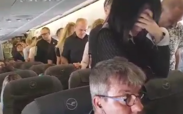 Un groupe d'Israéliens sur un vol de la  Lufthansa  se tiennent en silence dans le couloir au moment même où résonne en Israël la sirène qui ouvre Yom HaZikaron, le 1er mai 2017. (Crédit : capture d'écran YouTube)