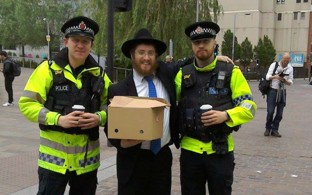 Le rabbin Shneur Cohen distribue des boissons chaudes et des viennoiseries à la police qui travaille sur les lieux de l'attentat qui a frappé Manchester, au Royaume-Uni, le 23 mai 2017. (Crédit :  Chabad of Manchester City Center)