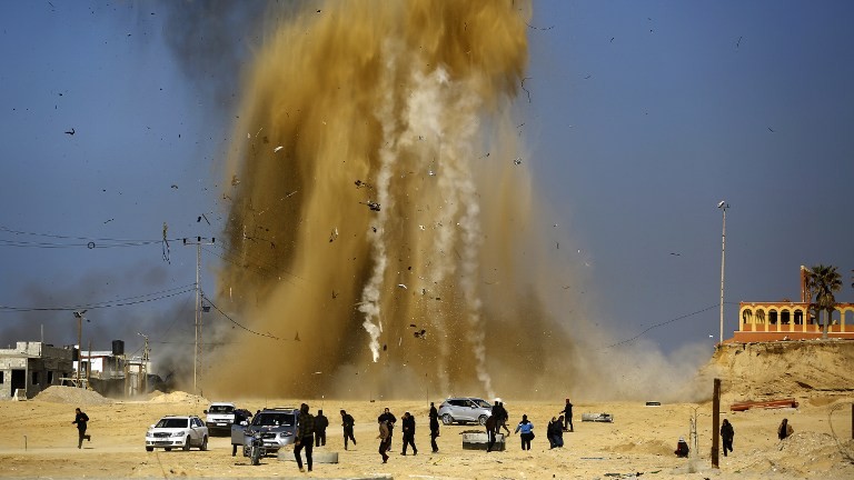Les Palestiniens courent pour se protéger du nuage de sable et de la fumée suite à une attaque aérienne israélienne sur un poste du Hamas dans le nord de la bande de Gaza le 6 février 2017 (Crédit : Mohammed Abed / AFP)