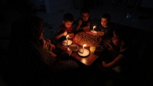 Une famille palestinienne dîne à la chandelle dans le camp de réfugiés de Rafah, dans le sud de la bande de Gaza, lors d'une panne de courant, 11 juin 2017 (Crédit : AFP / Said Khatib)