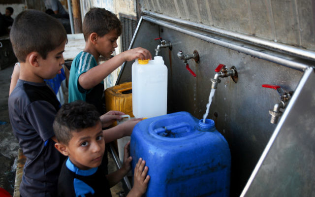 Des enfants palestiniens remplissent des jerrycans avec de l'eau potable provenant de robinets publics dans le sud de la bande de Gaza, le 11 juin 2017 (Crédit : Abed Rahim Khatib / Flash90)