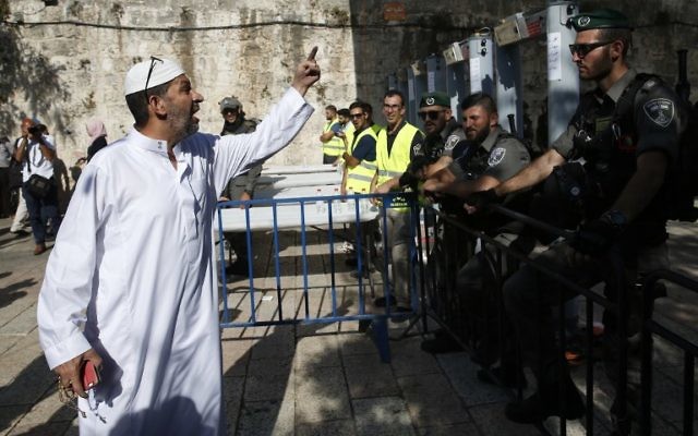 Un Palestinien interpelle les garde-frontières israéliens se tenant à côté des nouveaux détecteurs de métaux à l'entrée principale du mont du Temple dans la Vieille ville de Jérusalem, le 16 juillet 2017, après la réouverture de ce site ultra-sensible (Crédit :  AHMAD GHARABLI/AFP PHOTO)