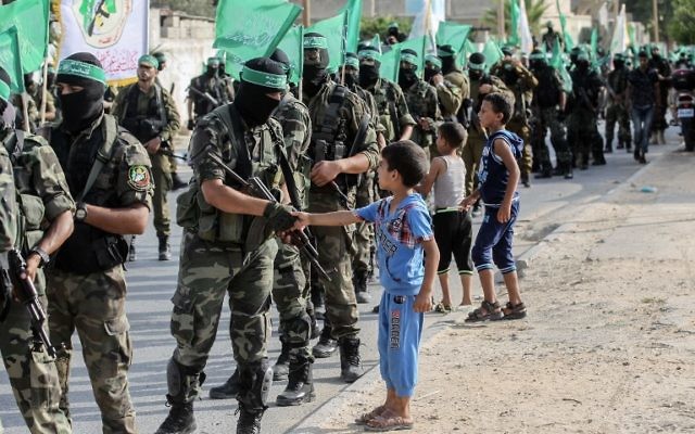 Des enfants palestiniens saluent les combattants des brigades Ezzedine al-Qassam, l'aile armée du groupe terroriste du Hamas dans les rues de la ville de Khan Yunis, dans le sud de la bande de Gaza, le 20 juillet 2017 (Crédit :  SAID KHATIB/AFP PHOTO)