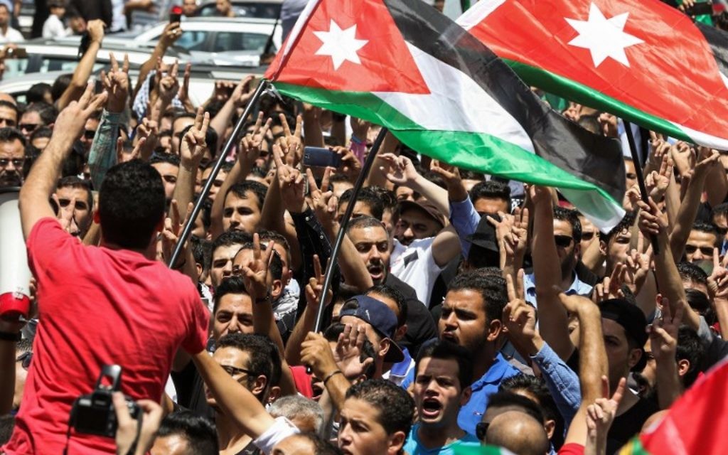 Des manifestants jordaniens brandissent des drapeaux nationaux et scandent des slogans durant une manifestation à proximité de l'ambassade israélienne dans la capitale d'Amman, le 28 juillet 2017, appelant à la fermeture de l'ambassade, au renvoi de l'ambassadeur et à l'annulation du traité de paix de 1994 avec Israël. (Crédit : KHALIL MAZRAAWI/AFP)