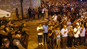 Les forces de sécurité israéliennes se tiennent aux côtés des fidèles musulmans palestiniens qui prient à l'extérieur de la Porte des Lions, près d'une entrée principale du mont du Temple dans la Vieille Ville de Jérusalem, le 24 juillet 2017. (Crédit : AFP / Ahmad GHARABLI)