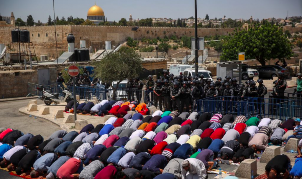 Les fidèles prient en dehors du mont du Temple sous l'oeil des forces de sécurité israéliennes, le 28 juillet 2017 (Crédit : Hadas Parush/Flash90)