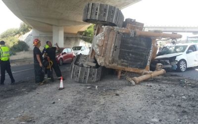 Un bulldozer qui a chuté de l'arrière d'un camion alors qu'il passait sous un pont sur la Route 1, le 21 août 2017 (Crédit : Police israélienne)