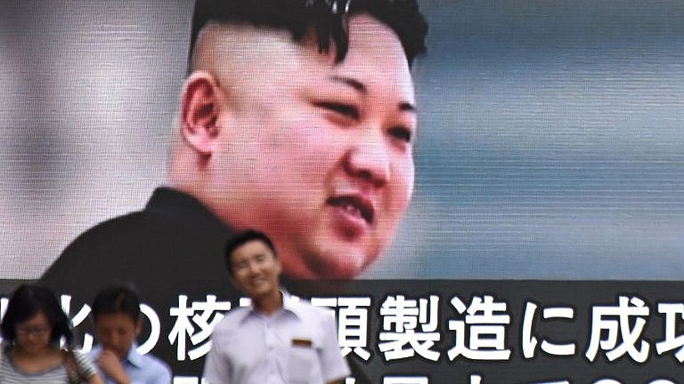 Des piétons devant une écran télévisé montrant Kim Jong-Un, le dictateur nord-coréen, à Tokyo, le 9 août 2017. (Crédit : Kazuhiro Nogi/AFP)