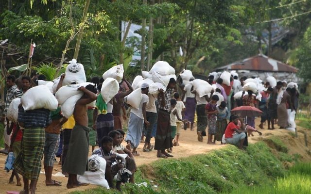 Des réfugiés musulmans Rohingya transportent de la nourriture distribuée par l'armée du Bangladesh au camp de réfugiés Balukhali près de Gumdhum, le 26 septembre 2017. (Crédit : AFP PHOTO/Dominique FAGET)