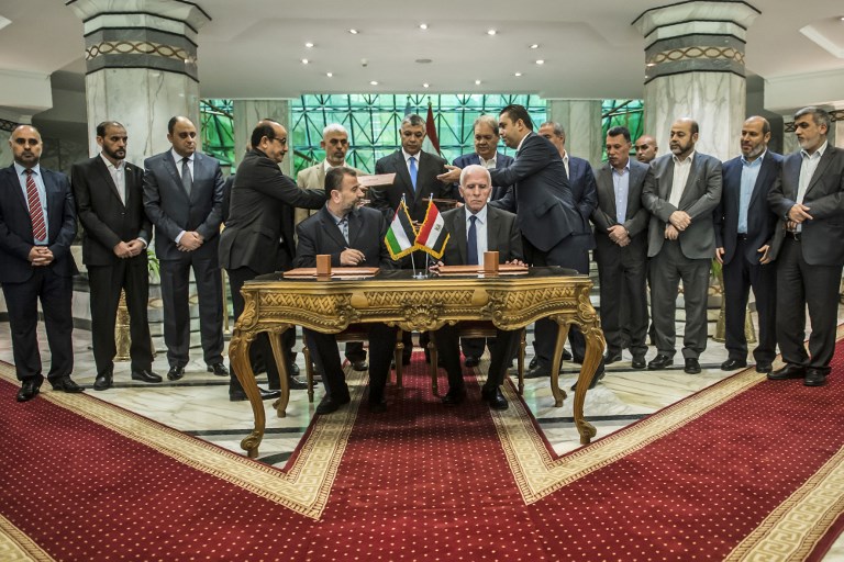 Saleh Arouri, assis à gauche, représentant du Hamas, et Azzam al-Ahmad, assis à droite, représentant du Fatah, pendant la signature d'un accord de réconciliation entre les factions palestiniennes rivales,  au Caire, le 12 octobre 2017. (Crédit : Khaled Desouki/AFP)