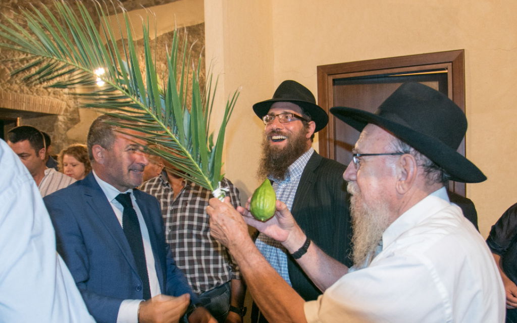 Les rabbins et les habitants locaux à l'événement organisé pour Souccot au Museo del Cedro (Musée Citron) à Santa Maria del Cedro. Le lulav est tenu par le rabbin Moshe Lazar (Crédit : Photographe Pino Lo Tufo/Autorisation de Angelo Adduci)