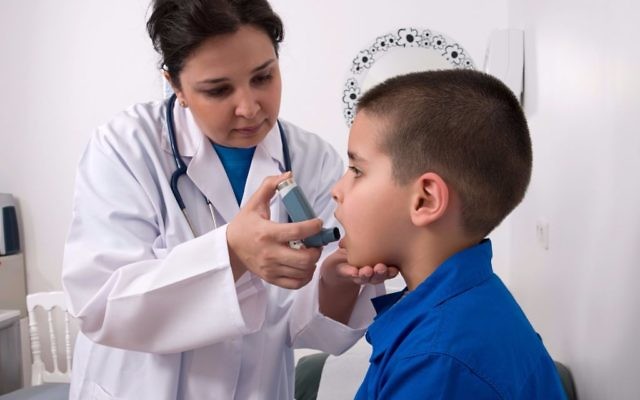 Un médecin montre à un petit garçon comment utiliser son inhalateur pour l'asthme. Illustration. (Crédit : LeventKonuk/iStock by Getty Images)