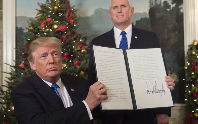 Le président américain Donald Trump tient un mémorandum signé après avoir prononcé son discours concernant Jérusalem depuis la Maison-Blanche, à Washington, le 6 décembre 2017, sous le regard du vice-président américain Mike Pence (Crédit : Saul Loeb / AFP)