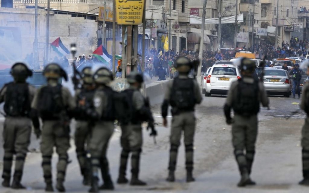 Les agents de police affrontent les émeutiers palestiniens durant des affrontements à proximité du poste de contrôle de Qalandiya en Cisjordanie, aux abords de Ramallah, le 15 décembre 2017 (Crédit : Abbas Momani/AFP)