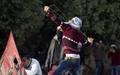 Un manifestant palestinien utilise une fronde pour jeter des pierres durant des affrontements avec les forces israéliennes de sécurité au checkpoint de Huwara, au sud de Naplouse, en Cisjordanie, le 15 décembre 2017 (Crédit :  AFP/Jaafar Ashtiyeh)