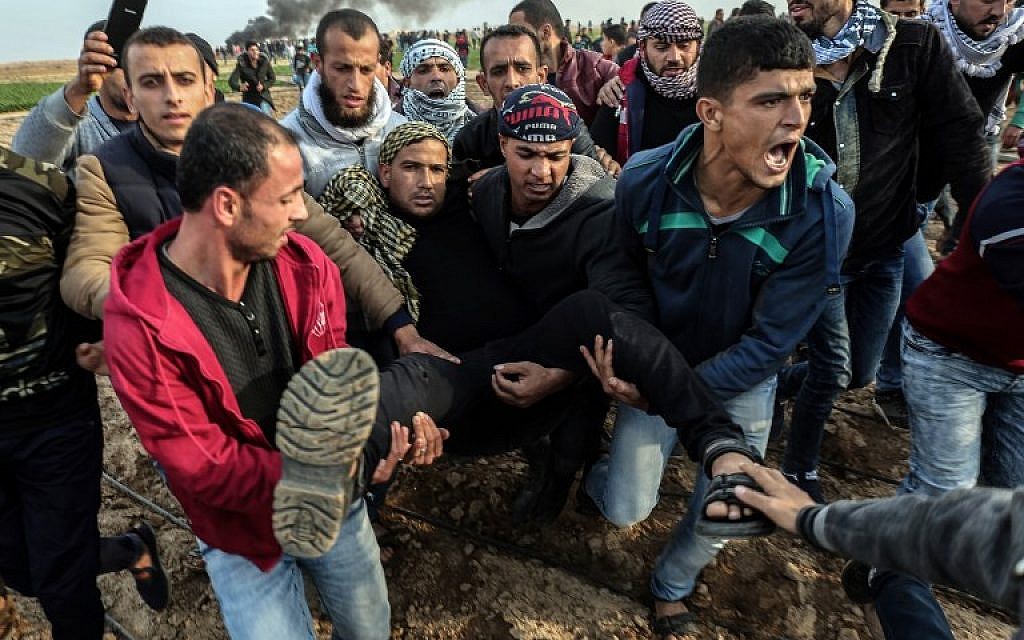 Des manifestants palestiniens transportent un blessé durant un affrontement contre les forces israéliennes près de la frontière entre Israël et Gaza dans la ville de Khan Yunis, dans le sud de Gaza, le 29 décembre 2017 (Crédit :  AFP PHOTO / SAID KHATIB)