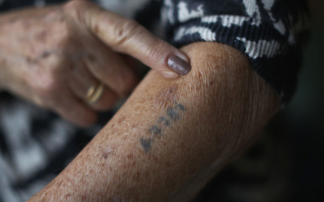 Une survivante de la Shoah montre son tatouage (Crédit : Christopher Furlong/Getty Images via JTA)