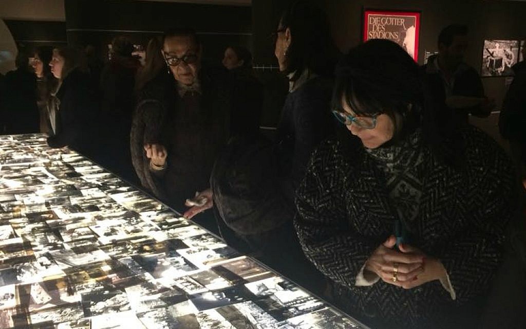 Les visiteurs regardent des centaines d'images datant de la période de l'Holocauste exposées sur une table lumineuse lors de l'ouverture de l'exposition 'Flash mémoriel' à Yad Vashem, le 24 janvier 2018 (Crédit : Renee Ghert-Zand / TOI)