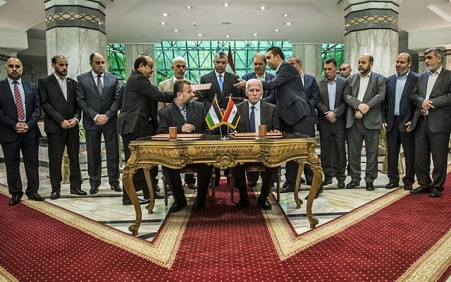 Le nouveau vice-président du Hamas Salah al-Arouri, (assis à gauche), et Azzam al-Ahmad, (assis à droite), signent un accord de réconciliation au Caire le 12 octobre 2017 alors que les deux mouvements rivaux palestiniens oeuvrent à mettre un terme à leur scission d'une décennie lors de négociations sous les auspices de l'Egypte (Crédit : AFP/Khaled Desouki)