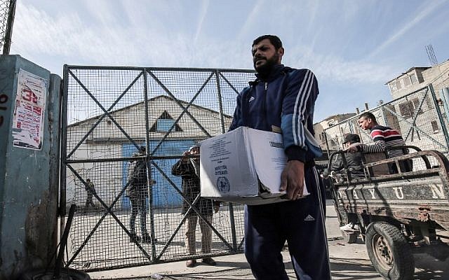 Les réfugiés palestiniens récoltent des colis humanitaires dans un centre de distribution des Nations unies à Rafah, dans le sud de la bande de Gaza, le 21 janvier 2018 (Crédit : AFP/ SAID KHATIB)