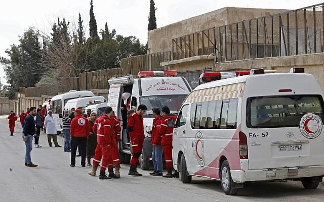Les ambulanciers du Croissant-Rouge syrien attendent à côté des ambulances prêtes à transporter les blessés au point de contrôle de Wafideen, en périphérie de Damas, le 28 février 2018, au cours d'une opération qui permettrait à quelque 400 000 personnes vivant dans la zone tenue par les rebelles de quitter l'enclave assiégée grâce à des couloirs sécurisés (Crédit : PHOTO AFP / LOUAI BESHARA)