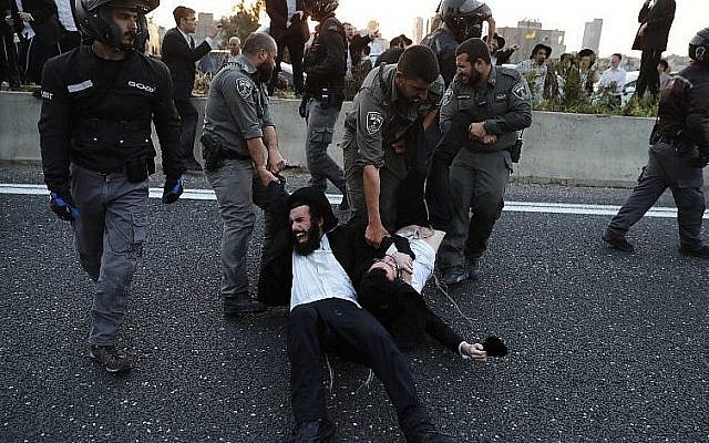 La police évacue des manifestants ultra-orthodoxes qui bloquent une route lors d'une manifestation contre l'enrôlement de l'armée dans la ville de Bnei Brak, près de Tel-Aviv, le 12 mars 2018 (Crédit : AFP PHOTO / Ahmad GHARABLI)