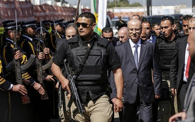 Le Premier ministre palestinien Rami Hamdallah, deuxième à droite, escorté de ses gardes du corps, est accueilli par les forces de police du Hamas, à gauche, à son arrivée à Gaza le 13 mars 2018. (AFP Photo/Mahmud Hams)