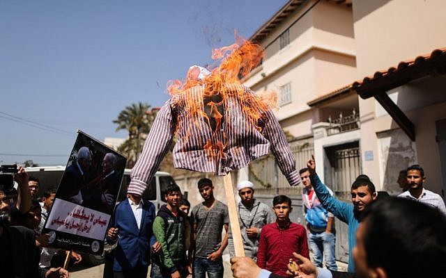 Des Palestiniens brûlent un mannequin représentant le président palestinien Mahmoud Abbas lors d'une manifestation dans la ville de Gaza le 21 mars 2018 (Crédit : AFP / MAHMUD HAMS)