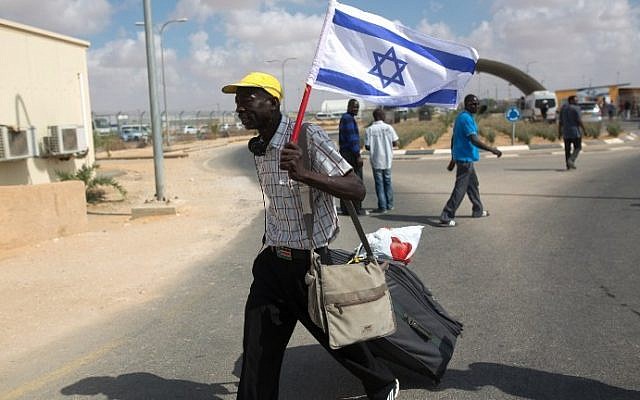 Un migrant africain clandestin marche avec un drapeau israélien suite à sa libération du centre de détention de Holot dans le désert israélien du Negev, le 25 août 2015 (Crédit : AFP PHOTO/MENAHEM KAHANA)