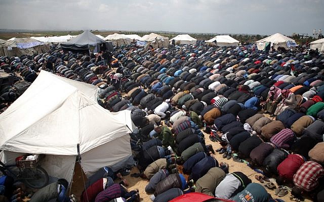 Les fidèles musulmans font la prière du vendredi, à midi, près d'une ville en tentes aux abords de la frontière avec Israël, à l'est de Jabalia, le 30 mars 2018 (Crédit : AFP/Mohammed Abed)