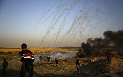Des manifestants palestiniens courent pour échapper au gaz lacrymogène lancé par les forces israéliennes durant des affrontements qui ont suivi une manifestation le long de la frontière avec Israël, à l'est de  Gaza City, le 1er avril 2018 (Crédit : Mohammed Abed/AFP)
