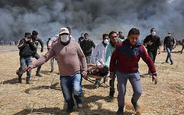 Photo d’illustration : un manifestant palestinien blessé est porté par des manifestants lors d'affrontements avec les forces de sécurité israéliennes près de la frontière avec Israël, à l'est de Khan Younis, dans le sud de la bande de Gaza, le 6 avril 2018 (AFP / Said Khatib)