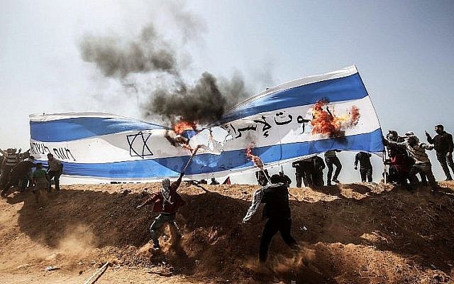 Des manifestants palestiniens brûlent un drapeau israélien lors d'affrontements avec les forces de sécurité israéliennes à la frontière entre Gaza et Israël, à l'est de Khan Younès, dans le sud de la bande de Gaza, le 6 avril 2018. (AFP PHOTO / DIT KHATIB)