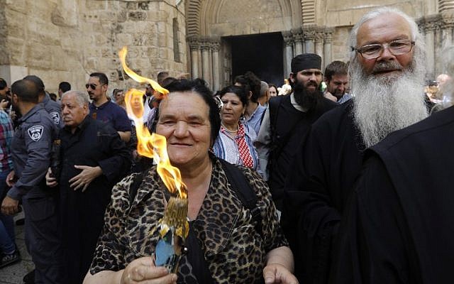 Les fidèles chrétiens orthodoxes tiennent des bougies allumées au "feu sacré" lors d'un rassemblement à l'église du Saint-Sépulcre de la Vieille Ville de Jérusalem lors de la Pâque orthodoxe, le 7 avril 2018 
 (Crédit : AFP PHOTO / GALI TIBBON)