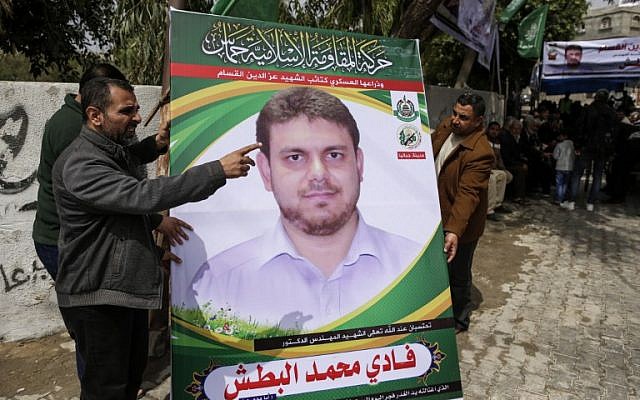 Une photo prise le 21 avril 2018 montre des hommes tenant une affiche du professeur palestinien de 35 ans et membre du Hamas Fadi Mohammad al-Batsh qui a été tué en Malaisie, devant la maison de sa famille à Jabaliya dans le nord de la bande de Gaza. (AFP PHOTO / MAHMUD HAMS)