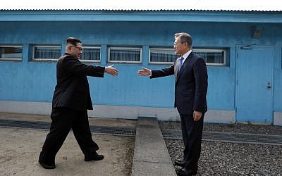 Poignée de main symbolique entre le dirigeant nord-coréen Kim Jong Un et le président sud-coréen Moon Jae-in, à la Ligne de Démarcation militaire qui divise leur pays avant leur sommet à Panmunjom, le 27 avril 2018. (Crédit : AFP / Korea Summit Press Pool / Korea Summit Press Pool)