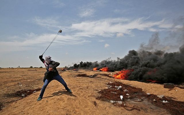 Un Palestinien armé d'une fronde jette des pierres aux soldats israéliens près de Khan Younis dans le sud de la bande de Gaza, au cours du cinquième vendredi consécutif d'émeutes massives le long de la frontière entre Gaza et Israël, le 27 avril 2018 (Crédit :  AFP Photo/Said Khatib)
