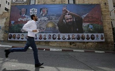 Un Palestinien passe devant une affiche avec le portrait du terroriste condamné et célèbre prisonnier palestinien Marwan Barghouti dans la ville de Ramallah, en Cisjordanie, le 3 mai 2017. (AFP/ ABBAS MOMANI)
