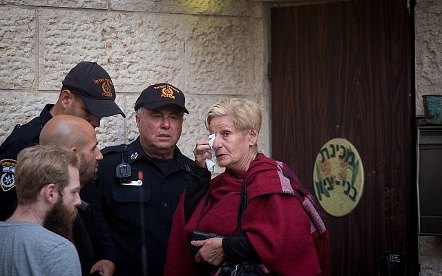 Une femme pleure aux côtés d'agents de police devant l'académie prémilitaire Benny Tzion de Tel Aviv qui avait organisé une randonnée qui a causé la mort de 9 adolescents dans la journée, le 26 avril 2018 (Crédit : Miriam Alster/Flash90)