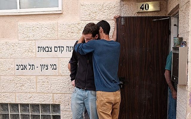 Des gens à l'entrée de l'académie prémilitaire Bnei Tzion de Tel Aviv après la mort de neuf jeunes entraînée par des inondations lors d'une randonnée organisée par l'institution dans le désert de Judée, le 26 avril 2018 (Crédit : Tomar Neudberg/Flash90)