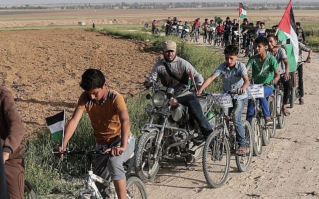 Des enfants palestiniens font du vélo près de la frontière avec Israël à la périphérie de Khan Younes dans le sud de la bande de Gaza, alors qu'ils participent à une course cycliste exigeant un "droit au retour" en Israël pour des millions de Palestiniens, le 26 mars 2018 (AFP / Said Khatib)