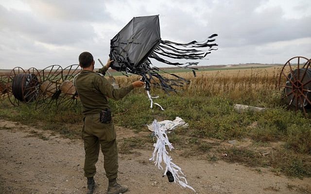 Un soldat israélien tient un cerf-volant lancé par des manifestants palestiniens depuis la frontière du côté de Gaza, transportant une bombe artisanale pour allumer des incendies en Israël, à proximité du kibboutz  Kfar Aza, le 24 avril 2018  (AFP PHOTO / Menahem KAHANA)