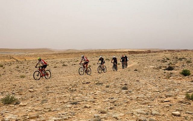 Des cyclistes traversent le désert du Néguev à Machtesh Ramon, le 6 mai 2018. (Crédit :AFP / MENAHEM KAHANA)