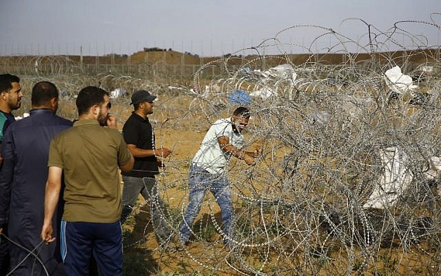 Un manifestant palestinien coupe une section de fil barbelé sur la clôture frontalière entre Israël et la bande de Gaza, à l'est de Jabalia, le 1er juin 2018 (Crédit :/ AFP PHOTO / Mohammed ABED)