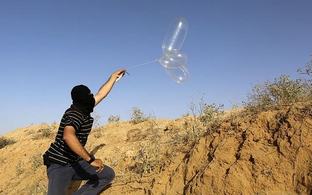 Un Palestinien masqué lance un ballon chargé de matières inflammables en direction d'Israël depuis la ville de Rafah, au sud de Gaza, le 17 juin 2018. (AFP Photo/Said Khatib)