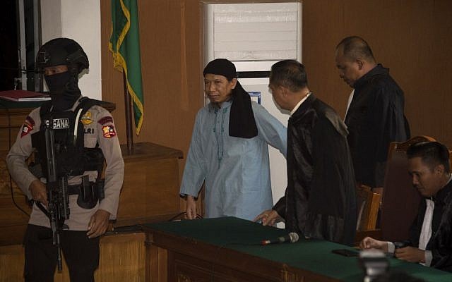 Un agent de police indonésien escorte Aman Abdurrahman, cerveau de l'attentat suicide de Jakarta en 2016, au tribunal de Jakarta, le 22 juin 2018. (Crédit : AFP / BAY ISMOYO)