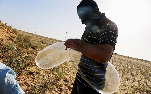 Un Palestinien masqué prépare des ballons auxquels seront attachés des matériaux inflammables et qui seront lancés en direction du territoire israélien, à Rafah, le 17 juin 2018. (Crédit : Abed Rahim Khatib/Flash90)