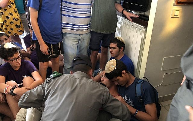 Un agent de la police des frontières demande à l'un des enfants résidents d'une maison, construite illégalement dans l'avant-poste de Netiv Haavot dans la zone du Gush Etzion en Cisjordanie, de quitter les lieux le 12 juin 2018. (Luke Tress/Times of Israel)