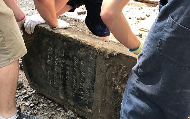 Des volontaires sauvent une pierre tombale juive utilisée pour paver une rue dans la ville de Lviv, l'une des 100 pierres tombales découvertes lors de travaux de voirie dans le centre de la ville en juin 2018. (Marla Raucher Osborn, Rohatyn Jewish Heritage/via JTA)